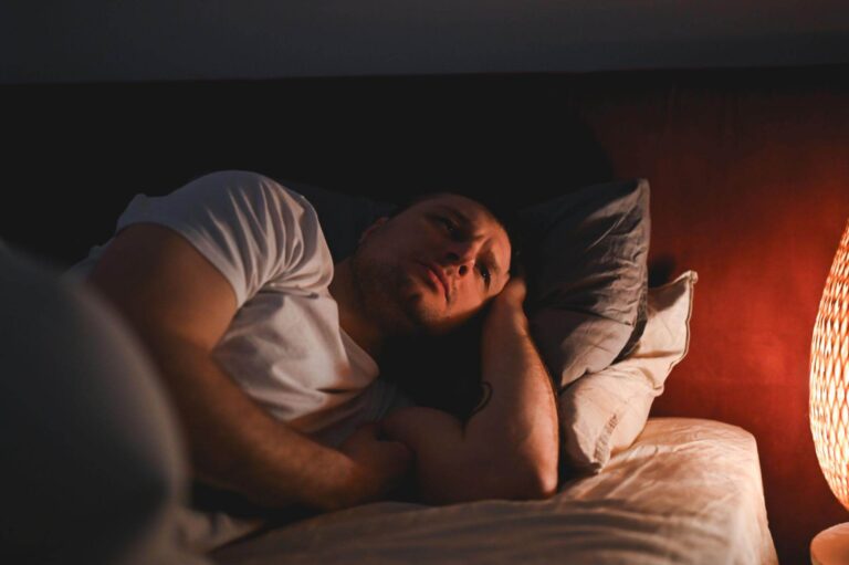 Exhausted person lying awake in bed despite feeling extremely tired