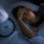 Person sitting on the edge of a bed after crying and struggling to sleep