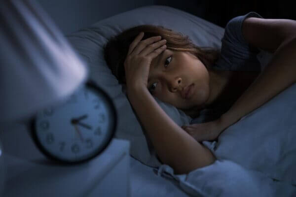 Person sitting on the edge of a bed after crying and struggling to sleep