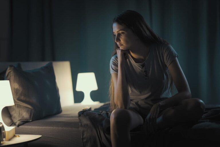Person sitting awake at night after socializing feeling mentally overstimulated