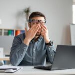 Person experiencing dry eyes after long computer screen use