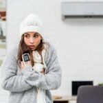 Woman feeling cold under office air conditioning vent