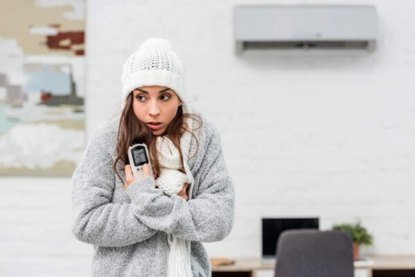 Woman feeling cold under office air conditioning vent