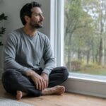 Person sitting quietly after meditation with a thoughtful distant gaze