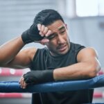 Boxer steadying himself against a wall after feeling dizzy following training