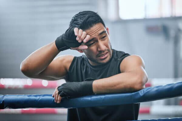 Boxer steadying himself against a wall after feeling dizzy following training