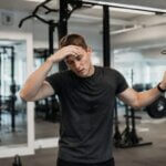 Person feeling lightheaded after pull-ups while recovering near a pull-up bar