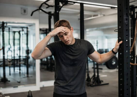 Person feeling lightheaded after pull-ups while recovering near a pull-up bar