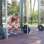 Man feeling dizzy after heavy squats in a gym