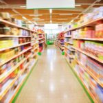 Person feeling dizzy under bright lights in a grocery store aisle