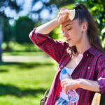 Person feeling exhausted after sun exposure while cooling down with water