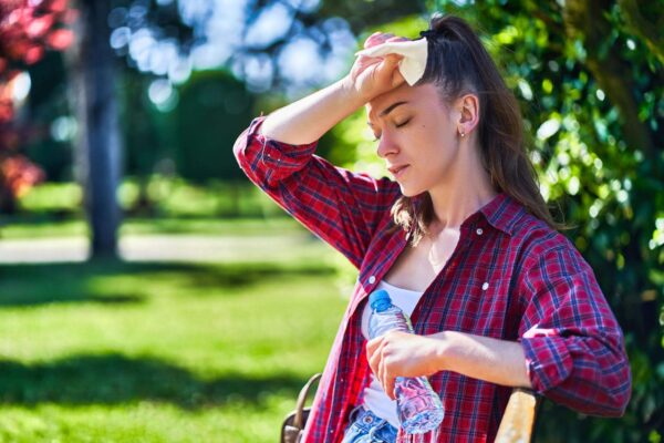 Person feeling exhausted after sun exposure while cooling down with water