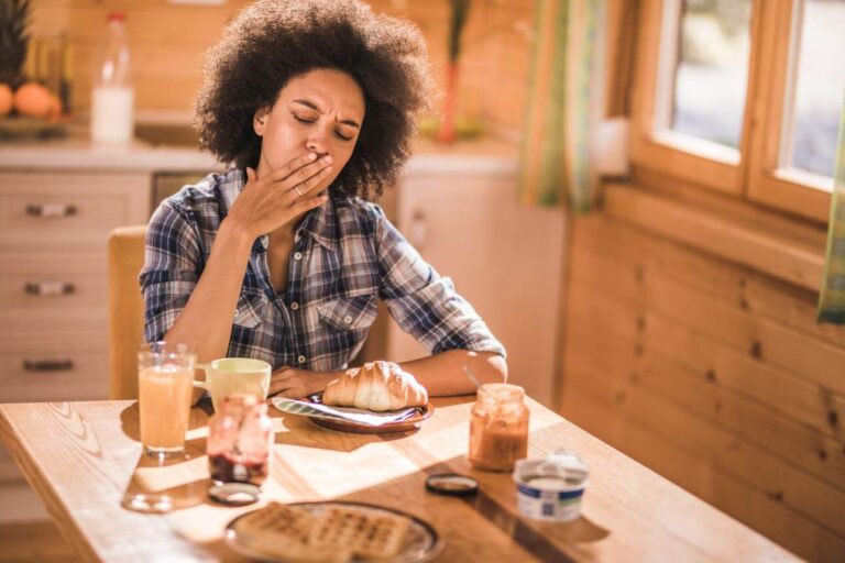 Person feeling nauseous shortly after eating breakfast at a kitchen table