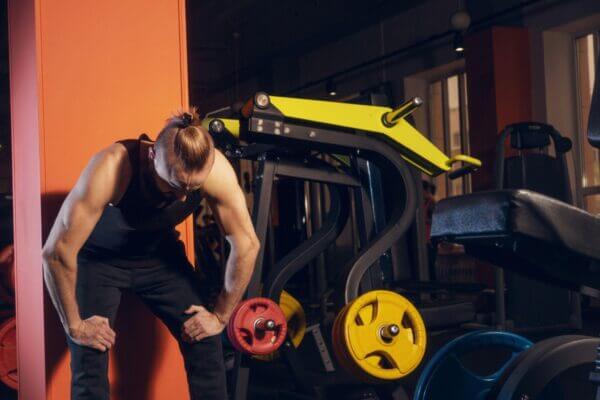 Person feeling nauseous and exhausted after an intense leg workout at the gym