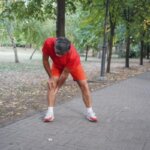 Person feeling sore after stretching hamstring muscles at home