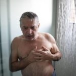 Person holding chest after noticing a racing heartbeat after a hot shower
