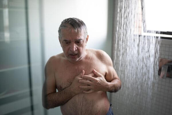 Person holding chest after noticing a racing heartbeat after a hot shower