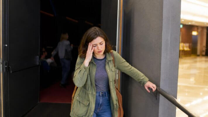 Person feeling dizzy after leaving a movie theater lobby