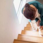 Person pausing on stairs feeling out of breath after climbing upstairs
