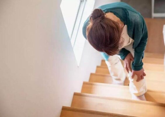 Person pausing on stairs feeling out of breath after climbing upstairs