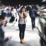 Person feeling overwhelmed in a crowded public place with sensory overload