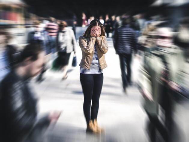 Person feeling overwhelmed in a crowded public place with sensory overload