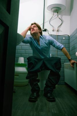 Person experiencing poop sweats and dizziness during a bowel movement
