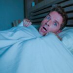 Person experiencing a sinking feeling while falling asleep in bed