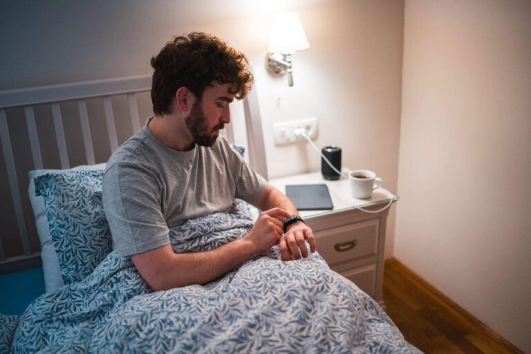 Person waking up tired while checking a good sleep score on a smartwatch