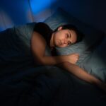 “Tired person lying in bed awake at night despite feeling exhausted”