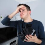 Person removing a VR headset while holding forehead from eye strain and pressure headache
