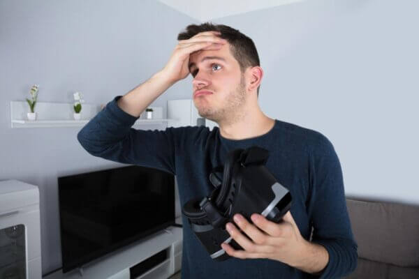 Person removing a VR headset while holding forehead from eye strain and pressure headache