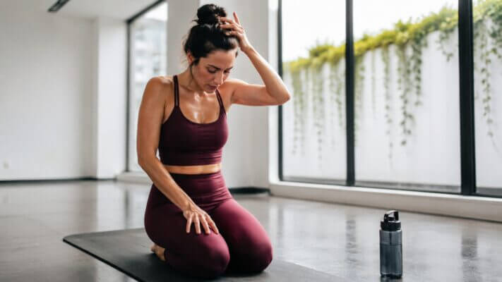 Woman resting after a hot yoga session with signs of shakiness and fatigue