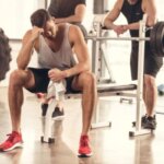 Man feeling lightheaded after a heavy bench press set in a gym