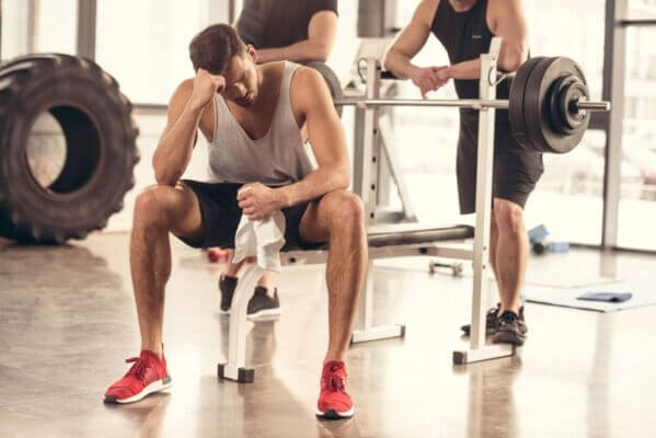 Man feeling lightheaded after a heavy bench press set in a gym