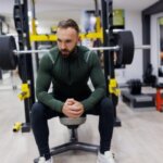 Athlete sitting on a bench press station feeling nauseous after a heavy set