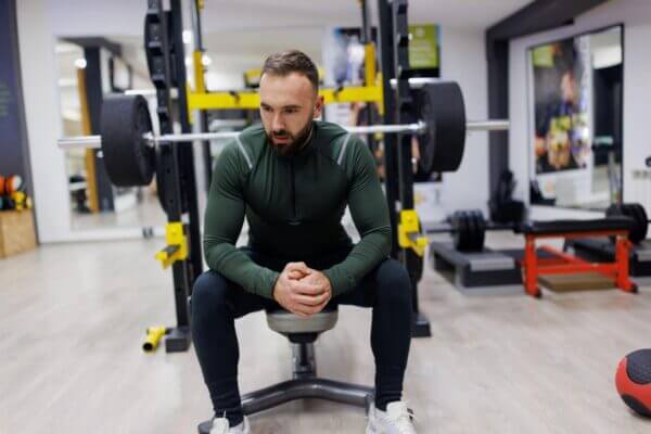 Athlete sitting on a bench press station feeling nauseous after a heavy set
