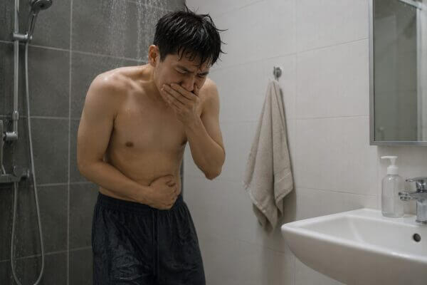 Person feeling nauseous after a cold shower in a bathroom