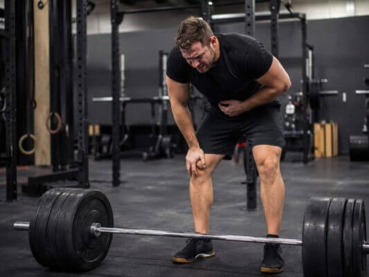 Athlete recovering after a heavy deadlift set and feeling nauseous