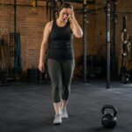 Person recovering after kettlebell swings and feeling lightheaded in a gym