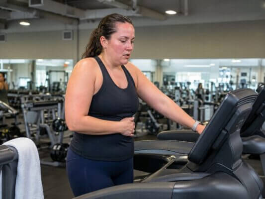 Woman slowing down during an incline treadmill workout because of nausea