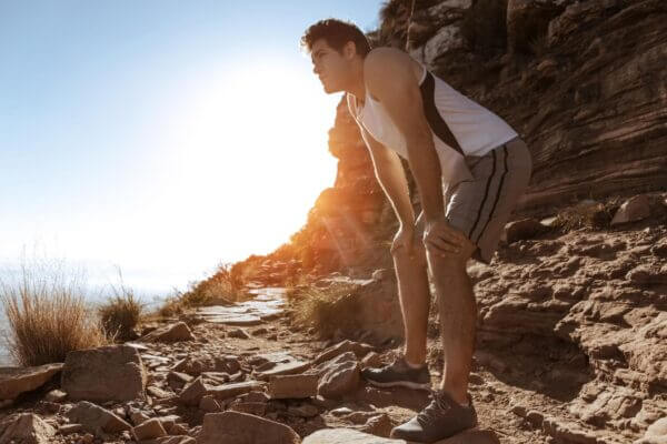 Person walking uphill and pausing to catch their breath on a trail