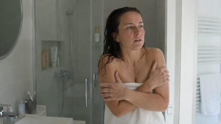 Person feeling shaky after a cold shower while wrapped in a towel