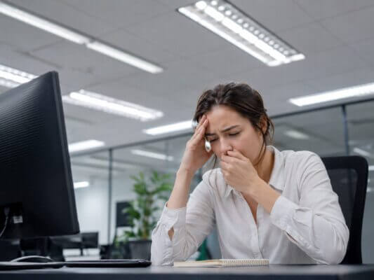 Person feeling nauseous under fluorescent office lighting