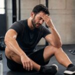 Athlete experiencing a headache after an intense HIIT workout in a gym