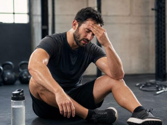 Athlete experiencing a headache after an intense HIIT workout in a gym
