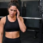 Athlete experiencing head pressure after a heavy squat set beside a barbell rack