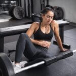 Athlete resting after hip thrust workout while feeling nauseous in a gym
