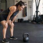 Person feeling nauseous after kettlebell swings in a gym