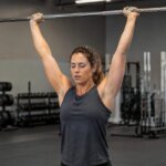Athlete experiencing brief dizziness at the top of an overhead press set